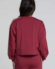 Back view of a woman wearing the Chaser Kloud Burnt Red Sweatshirt on a neutral background with pants