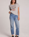 Full body front view of a woman wearing the Chaser Live Music Graphic Tee and blue jeans on a neutral background with hand on hip