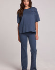 Full body front view of a woman wearing the Chaser Lunnah Dark Denim Top and blue pants on a neutral background