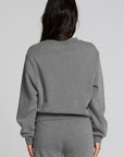 Back view of a woman wearing the Chaser Mini Star Glaze Sweatshirt on a neutral background with arms at sides in matching sweatpants