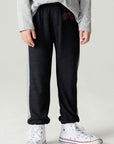 Front view of a boy wearing the Chaser Moto Pants Boys Jogger and white sneakers on a neutral background