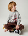 Seated boy wearing the Chaser Moto Patches Boys Tee on a neutral background