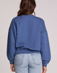 Back view of a woman wearing the Chaser New York Long Sleeve on a neutral background with arms lowered