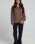 Full body front view of a woman wearing the Chaser Pine button down on a neutral background with black pants