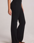 Side view of a woman wearing the Chaser Rhose Black Pants on a neutral background with arms lowered at sides