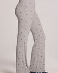 Side view of a woman wearing the Chaser Rhose Light Heather Grey Pants on a neutral background with arms on hips