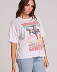 Side angle view of a woman wearing the Chaser Rodeo Show Tee on a neutral background with bluejeans