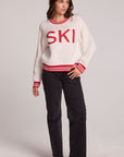 A full body front view of a woman wearing the Chaser Ski Longsleeve on a neutral background