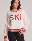 Front view of a woman wearing the Chaser Ski Longsleeve on a neutral background with black pants