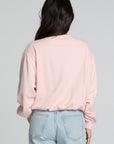 Back view of a woman wearing the Chaser Sporty Patches Long Sleeve Top and jeans on a neutral background