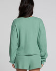 Back view of a woman wearing the Chaser Suzzans Verdelle Sweatshirt on a neutral background with shorts