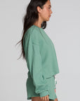 Side view of a woman wearing the Chaser Suzzans Verdelle Sweatshirt on a neutral background with matching shorts