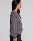 Back view of a woman wearing the Chaser The Rolling Stones 78 Tour Cropped Sweatshirt on a neutral background with black pants