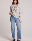 Full body view of a woman wearing the Chaser The Rolling Stones Long Sleeve Tee on a neutral background with hand on one hip and blue jeans