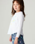 Side view of a girl wearing the Chaser Under The Stars Girls Tee on a neutral background with hands on legs
