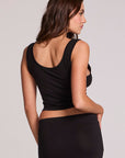 Back view of a woman wearing the Chaser Verze Black Top on a neutral background with hand on hip