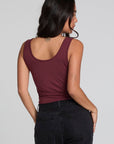 Back view of a tattooed woman wearing the Chaser Verze Brick Tank and jeans on a neutral background