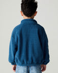 Back view of a boy wearing the Chaser White Bolts Boys Jacket and jeans on a neutral background