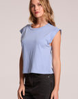 Side angle view of a woman wearing the Chaser Cropped Cap Sleeve Blue Hydrangea Crewneck Tee on a neutral background