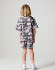 Full body back view of a boy wearing the Chaser Dusty Camo Tee on a neutral background