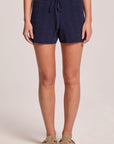 A front view of a woman wearing the Chaser Evie Admiral Shorts and clogs on a neutral background