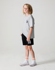A full body side angle view of a boy wearing the Chaser Go Team Shorts on a neutral background
