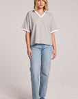 A full body view of a woman wearing the Chaser Heather Grey Eden Tee and sneakers on a neutral background