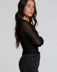 Side view of a woman wearing the Chaser Kevin Black Longsleeve on a neutral background with black pants