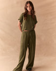 Full front view of Lee Trouser in bronze green with wide-leg silhouette and relaxed drape with matching tee against a beige background