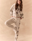 Full front view of NYC Stars Joggers in Heather Grey with black star print down each leg and matching top, styled for a casual lounge look, against a beige background