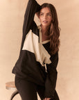Front view of woman wearing a black and white Chico long sleeve with striped design against a beige background