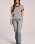 Front view of a woman wearing the Chaser Rambler Streaky Grey and Pine Tee and sneakers on a neutral background