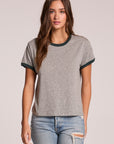 Front view of a woman wearing the Chaser Rambler Streaky Grey and Pine Tee and jeans on a neutral background