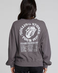Back view of a woman wearing the Chaser The Rolling Stones 78 Tour Cropped Sweatshirt on a neutral background with pants