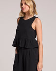 Side angle view of a blonde woman wearing a black Chaser Liberty tank set on a neutral background