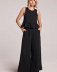 Front full view of a woman wearing a black Chaser Liberty tank set, pants, and slides on a neutral background