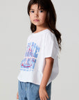 Side angle view of a girl wearing the Chaser Willie Nelson Cowgirl Tee on a neutral background
