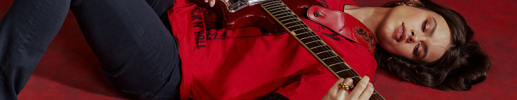 Person in red shirt playing guitar on a red background with Labor Day sale text overlay.