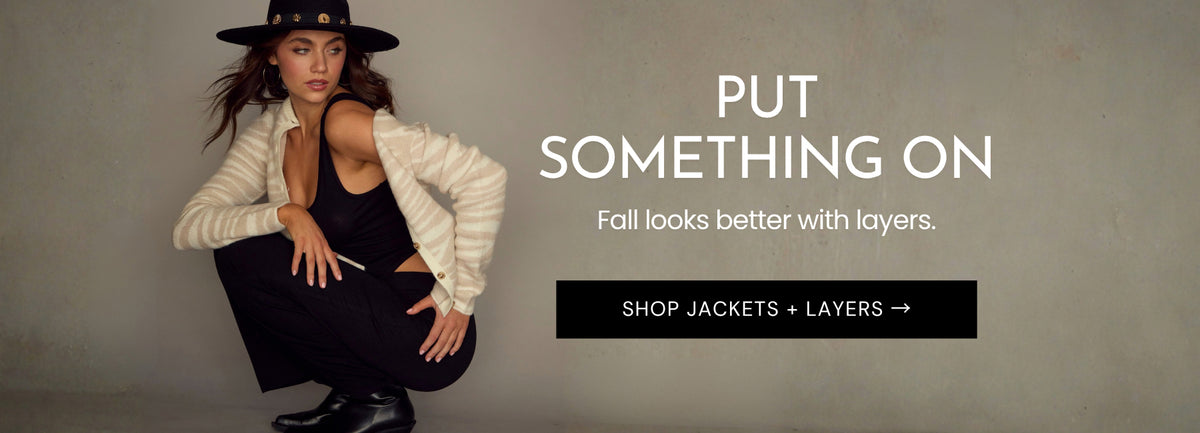 Model crouching in Chaser’s Zebra Dream Cardigan layered over the black Verze Top and Eloyse Skirt for the Put Something On Fall layers collection