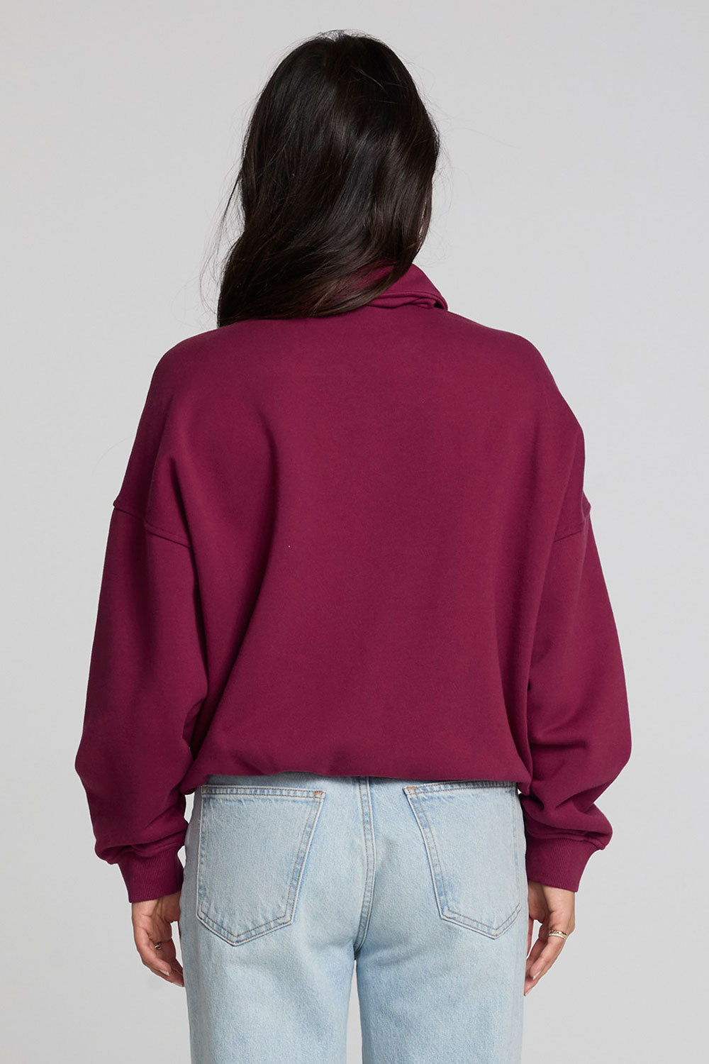 Back view of a woman wearing the Chaser 1986 Ski Club Long Sleeve and jeans on a neutral background