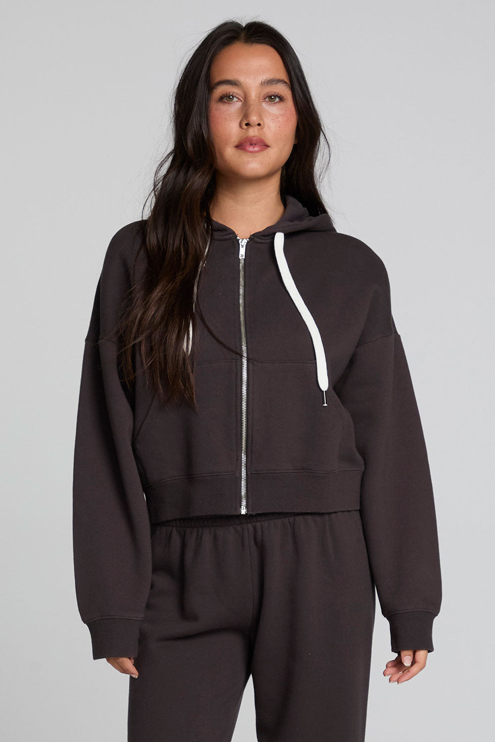 Front view of a woman wearing the Chaser  Abilene Dark Heather Grey Zip Up on a neutral background