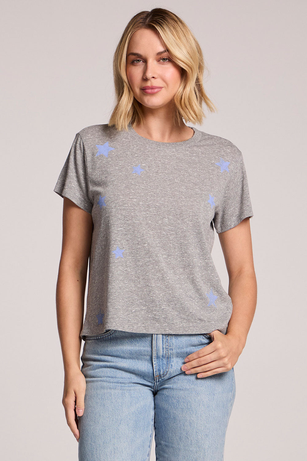 Front view of a woman wearing the Chaser  Allover Stars Tee and jeans on a neutral background
