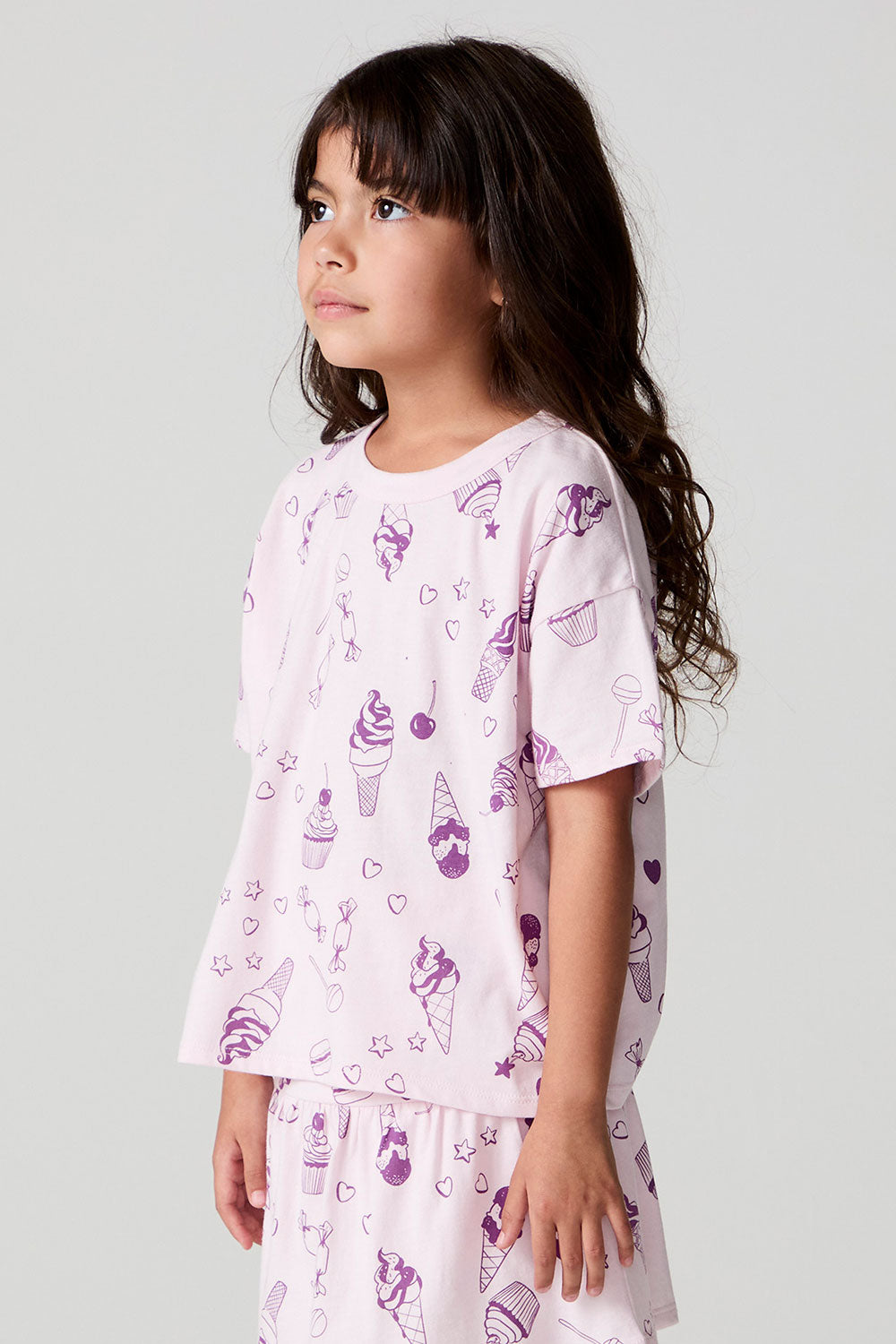 Side view of a girl wearing the Chaser Allover Sweets Tee and matching skort on a neutral background