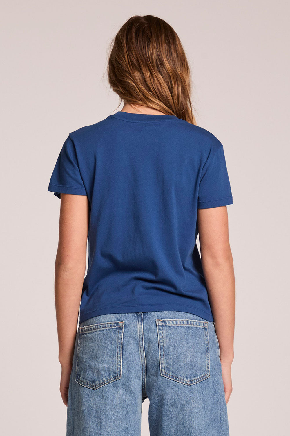 Back view of a woman wearing the Chaser   Aperitivo Tee on a neutral background