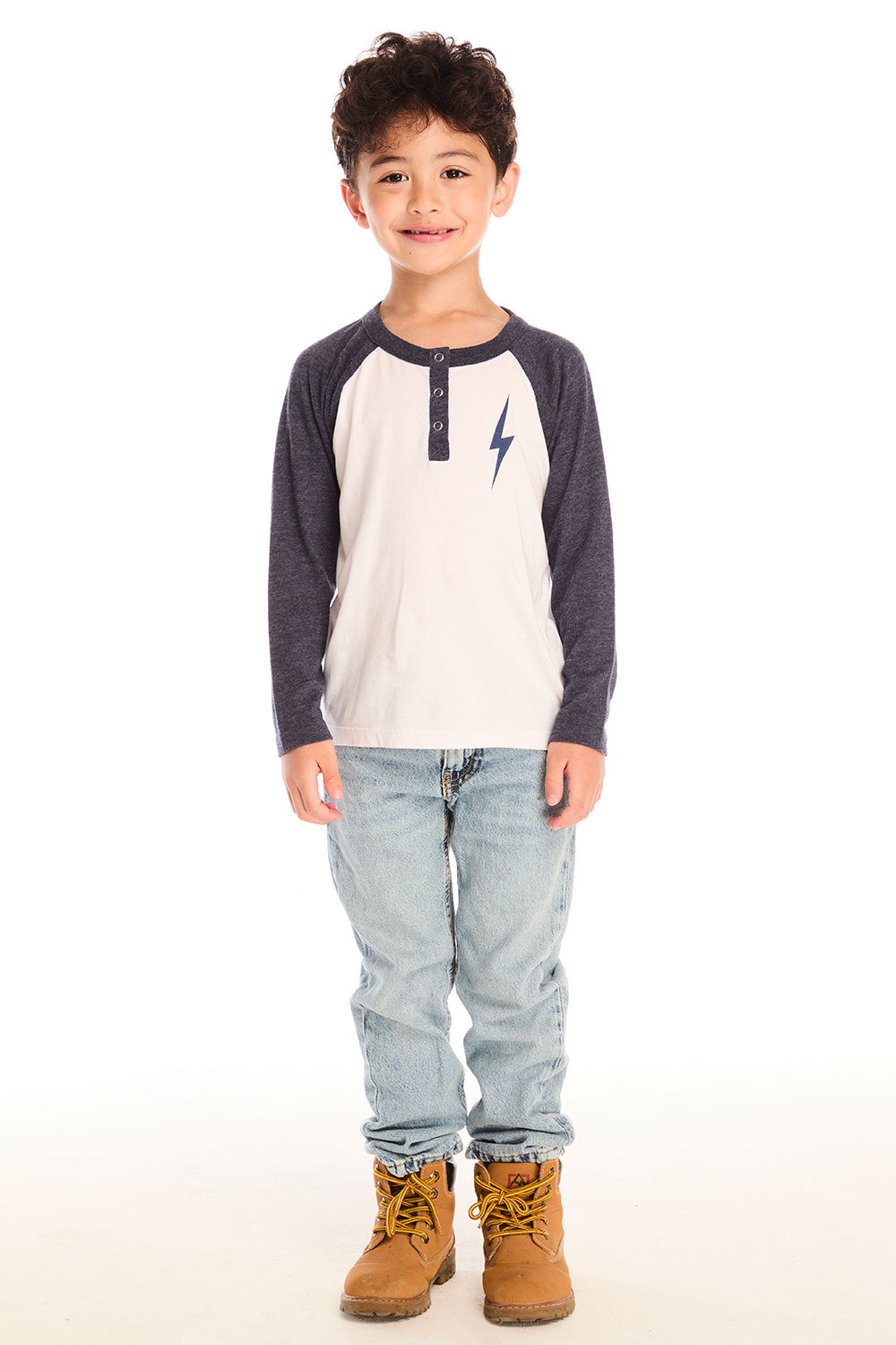 Full body view of boy wearing Chaser’s Lightning Bolt henley long sleeve top with jeans and brown boots on a white background