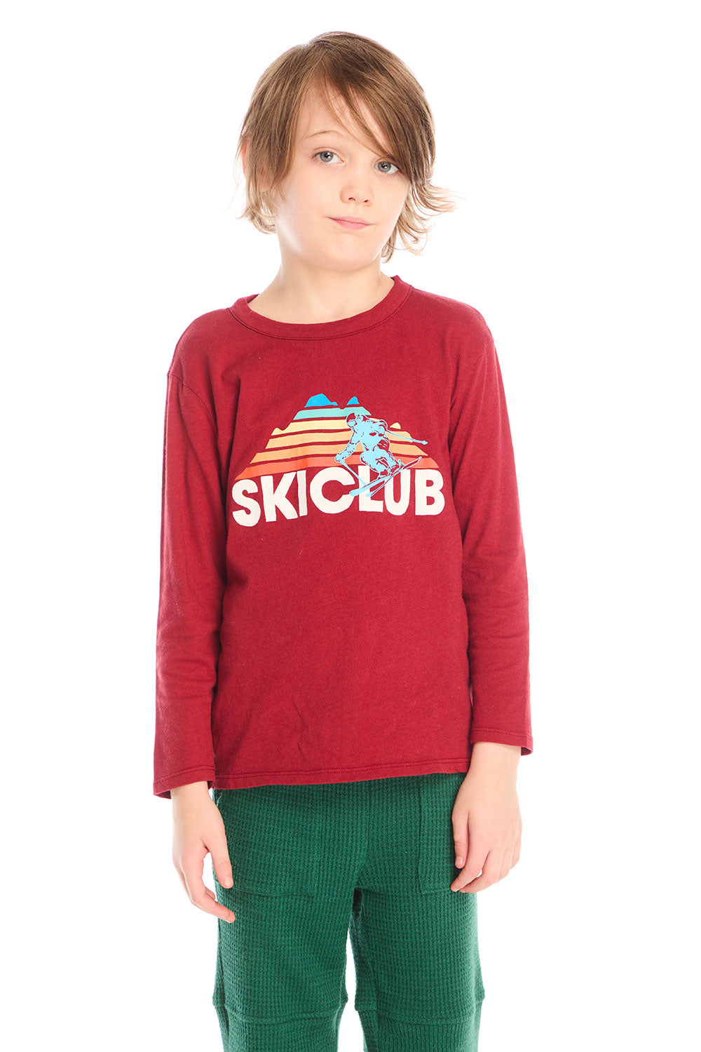 Boy wearing Chaser’s Ski Club red pullover long sleeve with “SKICLUB” text and colorful mountain silhouette graphic on a white background