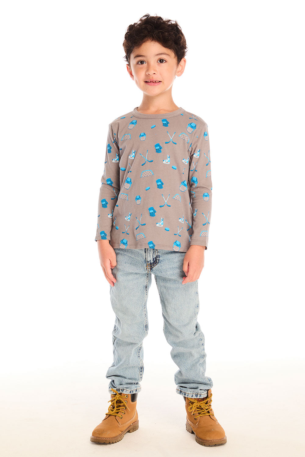 Full body view of boy wearing Chaser’s Hockey Champ patterned long-sleeve top with jeans and boots on a white background