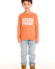 Full body view of boy wearing Chaser’s Raceway Speed orange long-sleeve top with a race car graphic and light blue jeans on a white background