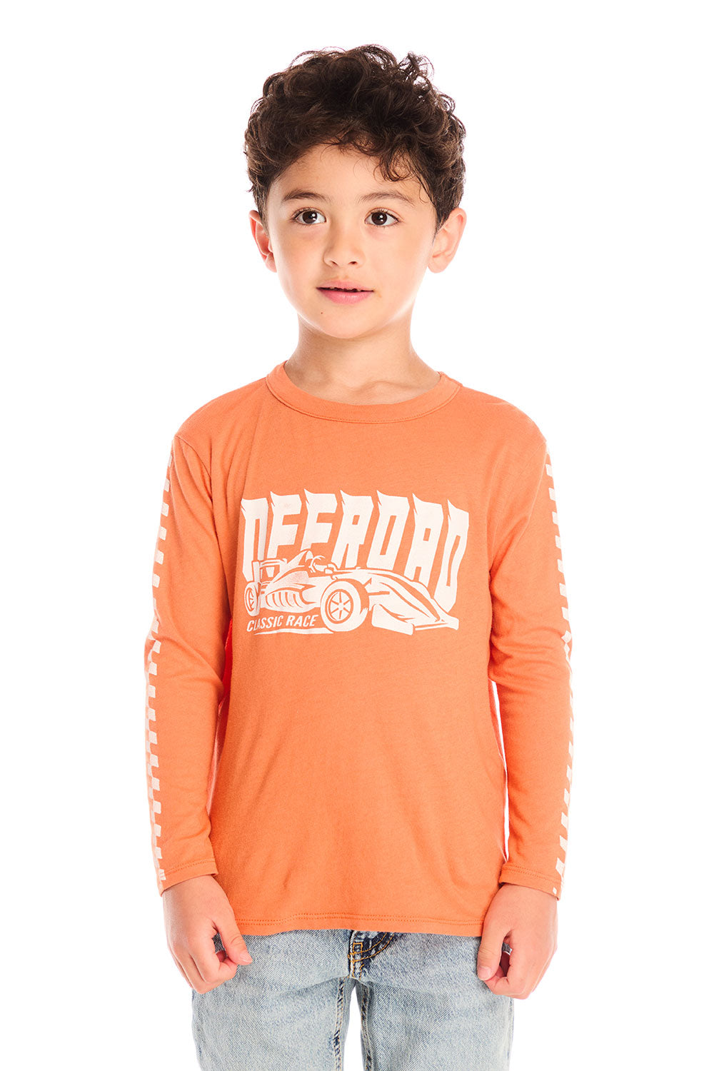 Boy wearing Chaser’s Raceway Speed orange long-sleeve top with a race car graphic and light blue jeans on a white background