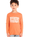 Boy wearing Chaser’s Raceway Speed orange long-sleeve top with a race car graphic and light blue jeans on a white background